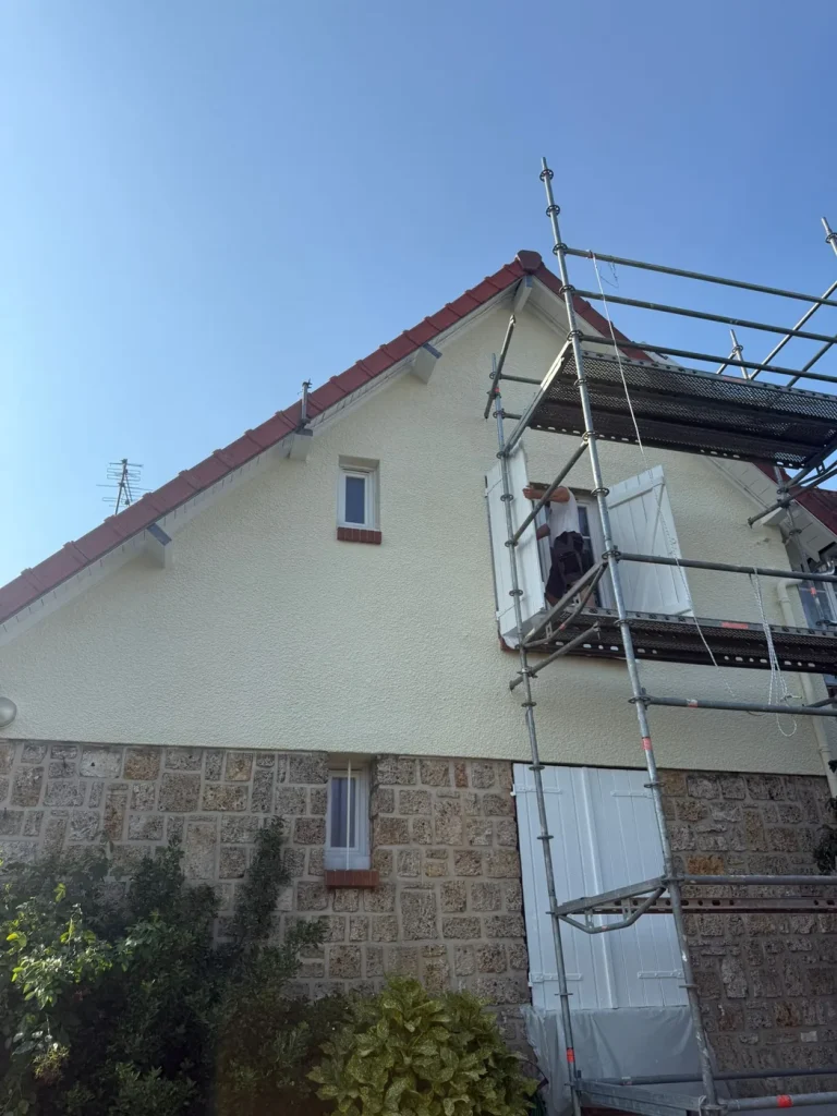 Maison en pierre et enduit sous échafaudage pendant des travaux de toiture